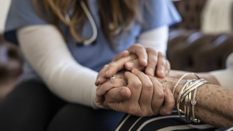 Infirmière tenant les mains d'une vieille femme