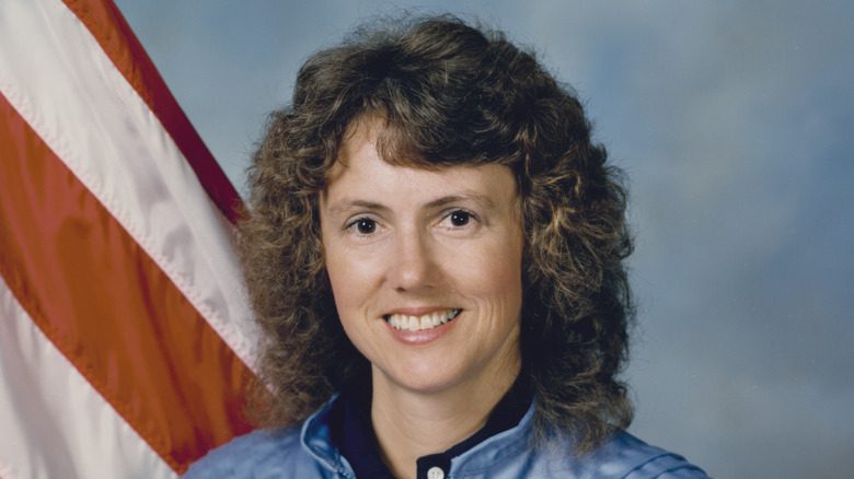 Christa McAuliffe souriante devant un drapeau