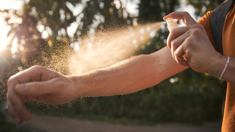 Person spraying mosquito spray