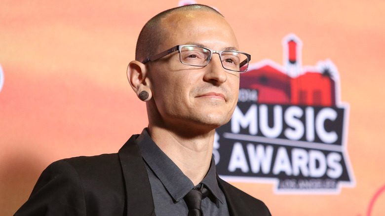 Chester Bennington wearing glasses, a suit, and tie