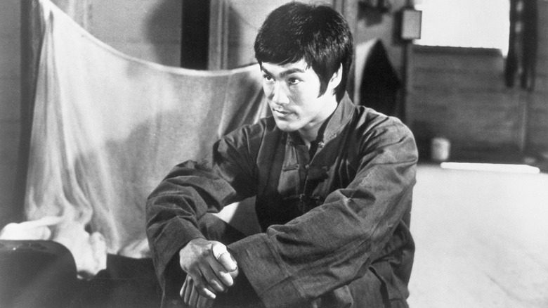 Bruce Lee seated in dark outfit