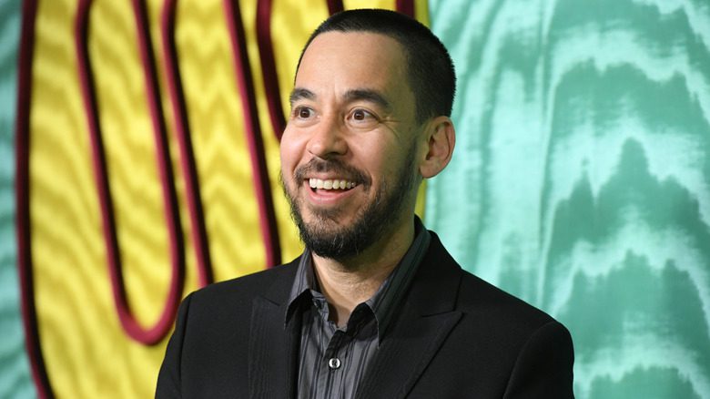 Mike Shinoda portant une chemise soignée et souriant